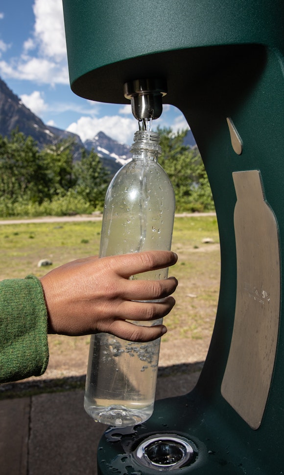 A person refills a water bottle at a water bottle refill station