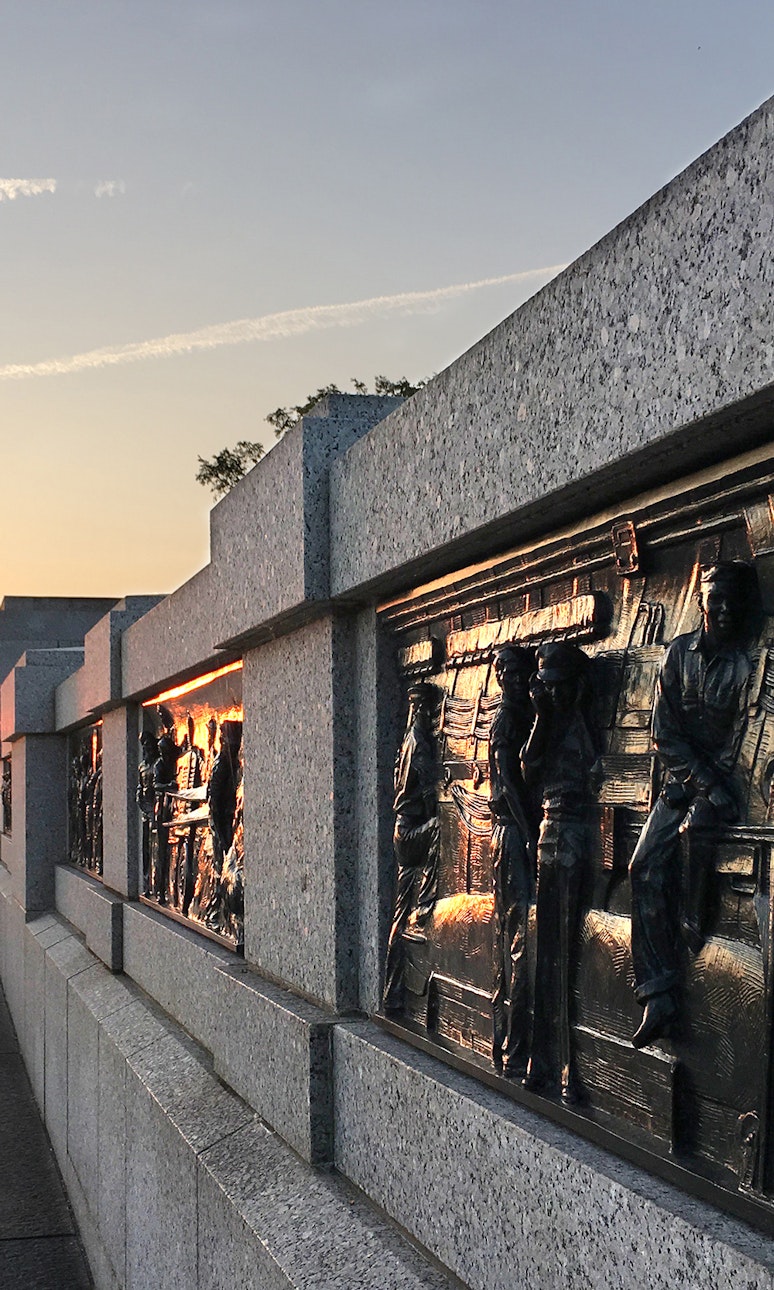 Bias relief depicting the Pacific on the World War II Memorial. In the distance, the Washington Monument against a sunset