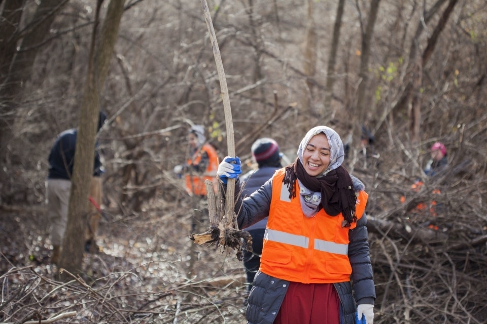 Volunteer wearing an orange vest holding a piece of debris