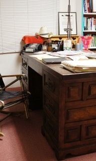 Office with large wooden desk and a jacket hanging off the back of a chair