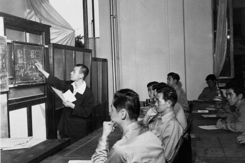 Historical photo of people sitting in a classroom, learning
