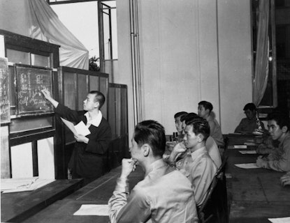 Historical photo of people sitting in a classroom, learning