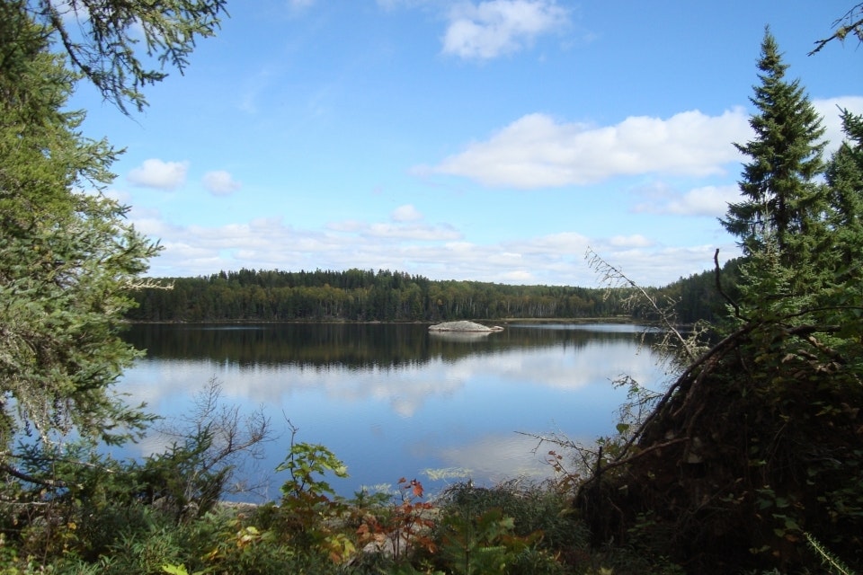 A blue sky reflects on a still lake
