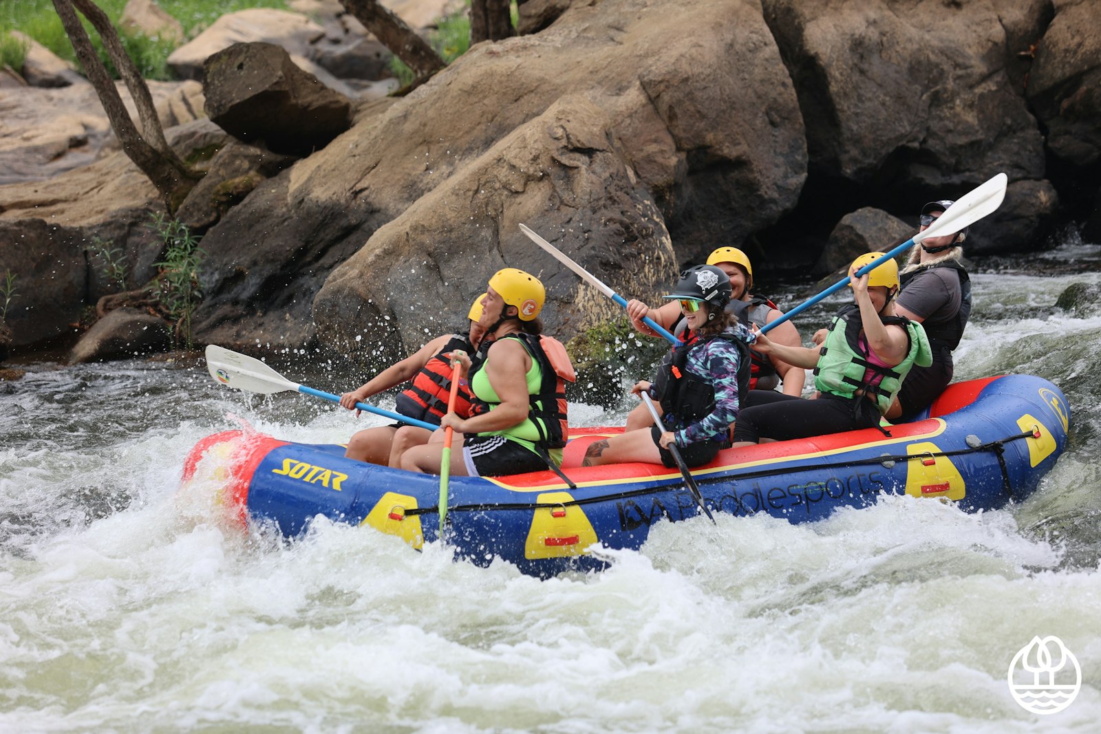 Six people in whitewater raft paddle down rapids