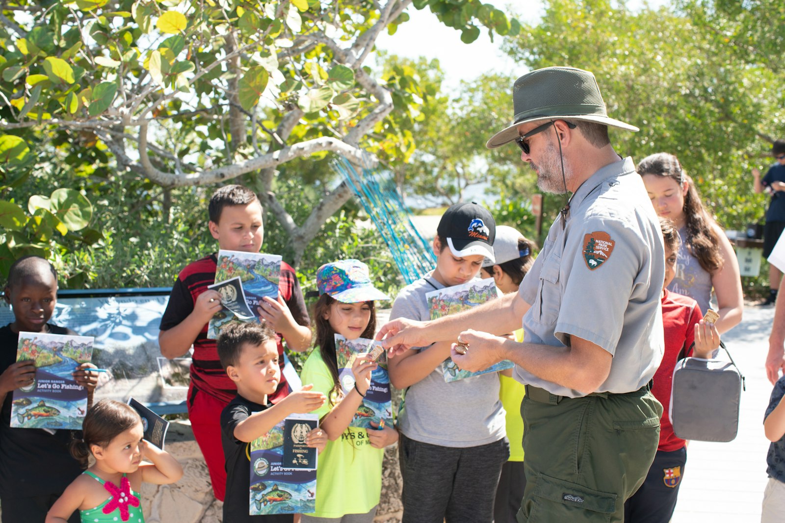 A park ranger and a group of young visitors with Junior Ranger Angler booklets