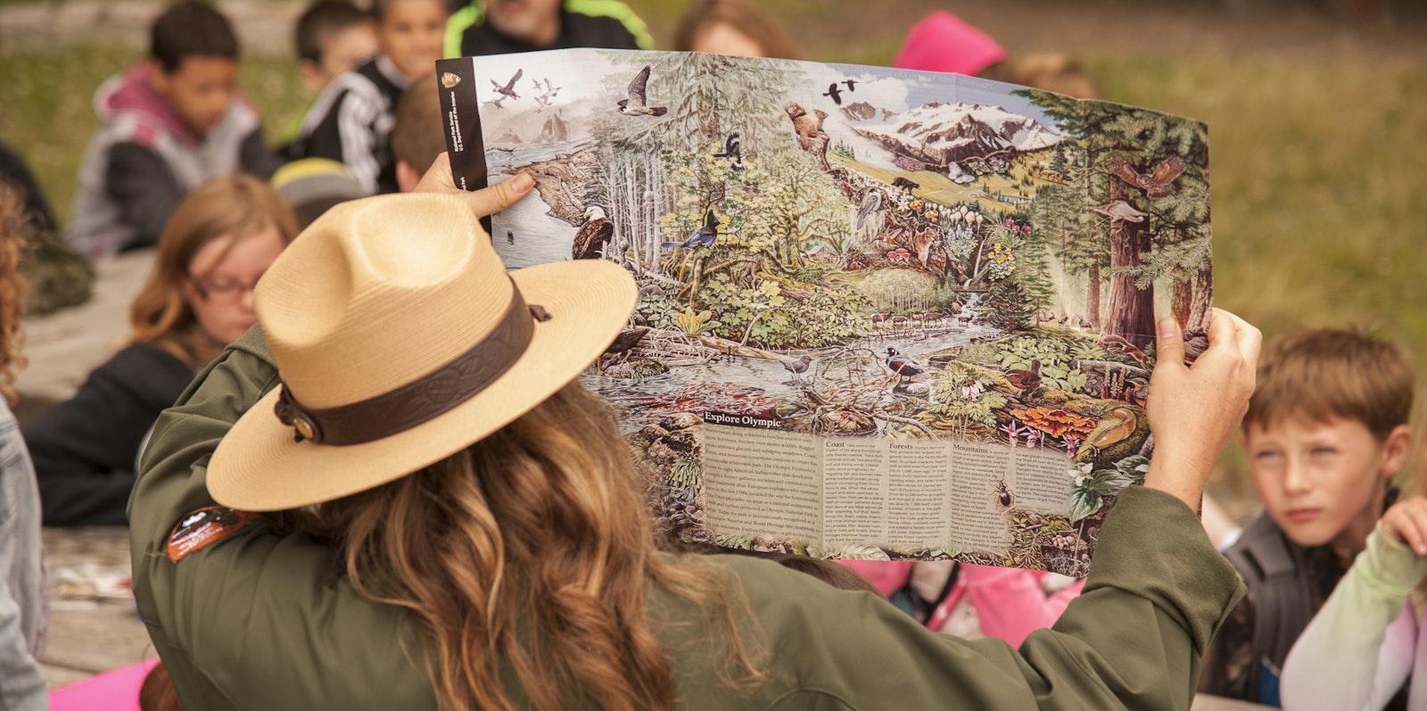 Students listen to a park ranger, who holds up a map to the group