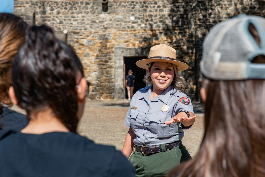 A uniformed park ranger talks to a group of students