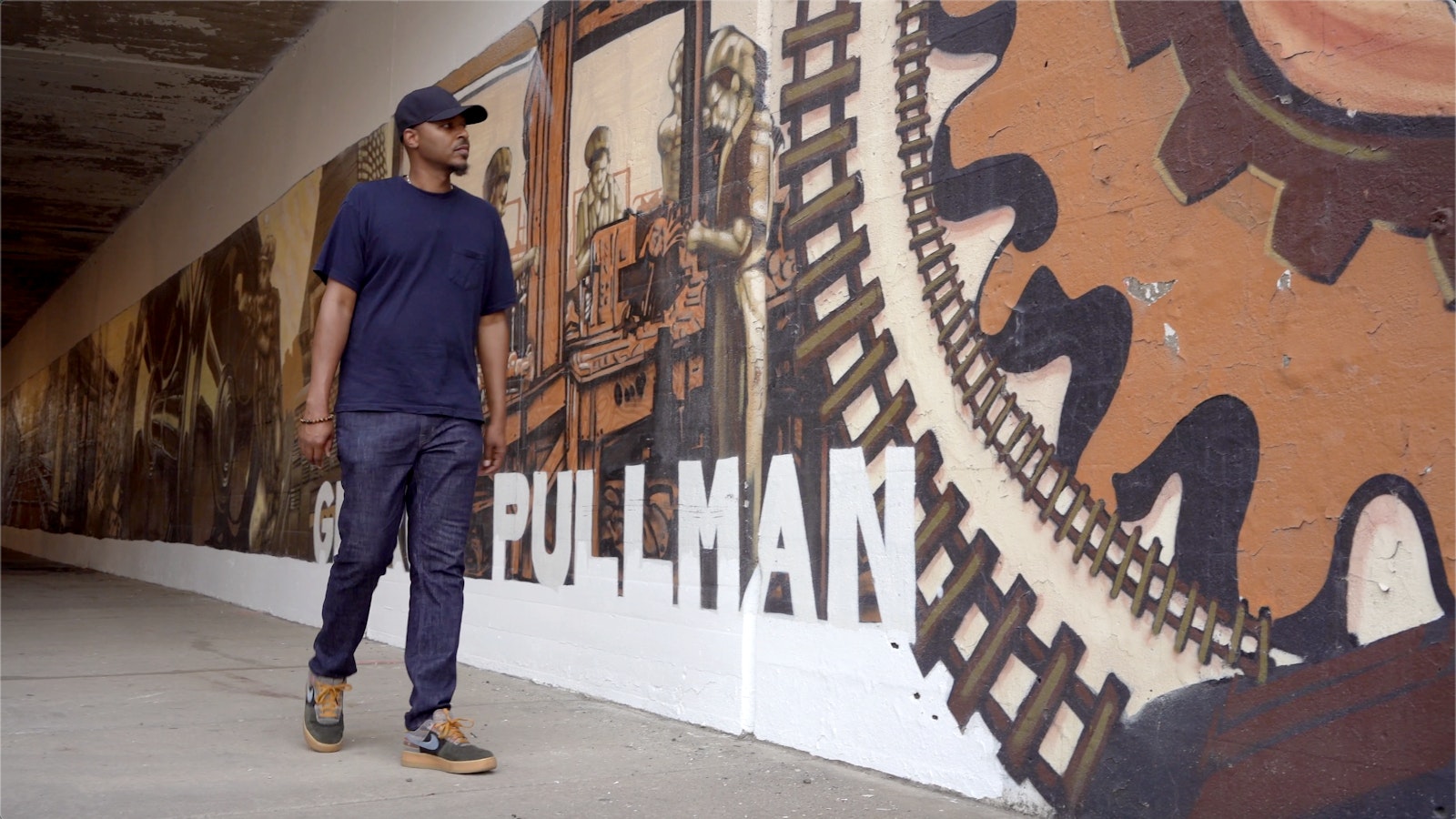 Artist Joe Nelson walks by a mural in Pullman National Monument