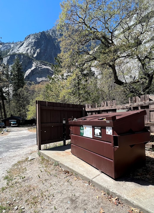 Brown compost bin, with the lid closed, at the foot of a mountain