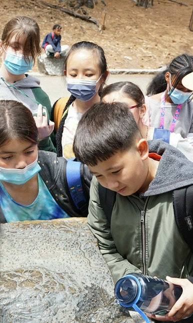 Students and a park ranger gather around a rock