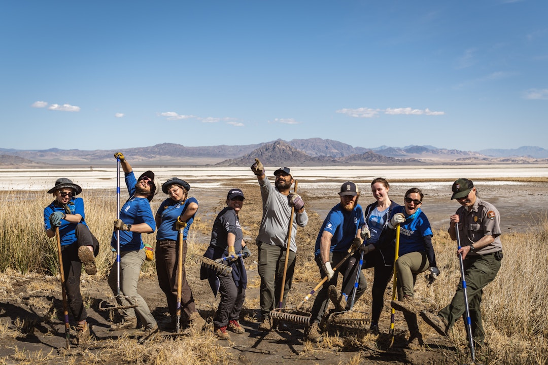 A group of service corps crew members pose for a "silly" photograph, bending into different stances and postures. They all wear matching blue shirts.