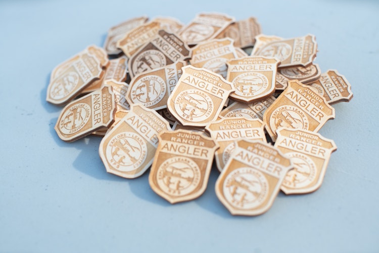 A pile of Junior Ranger Angler badges