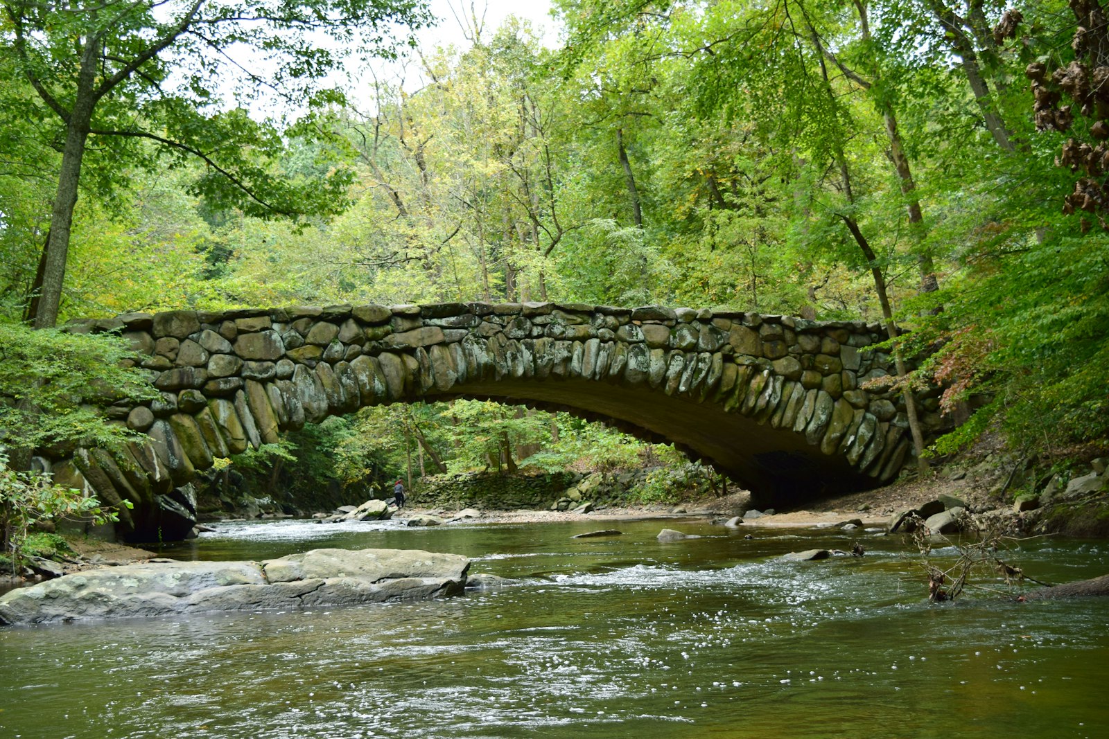 A stone bridge stretches over a calm creek