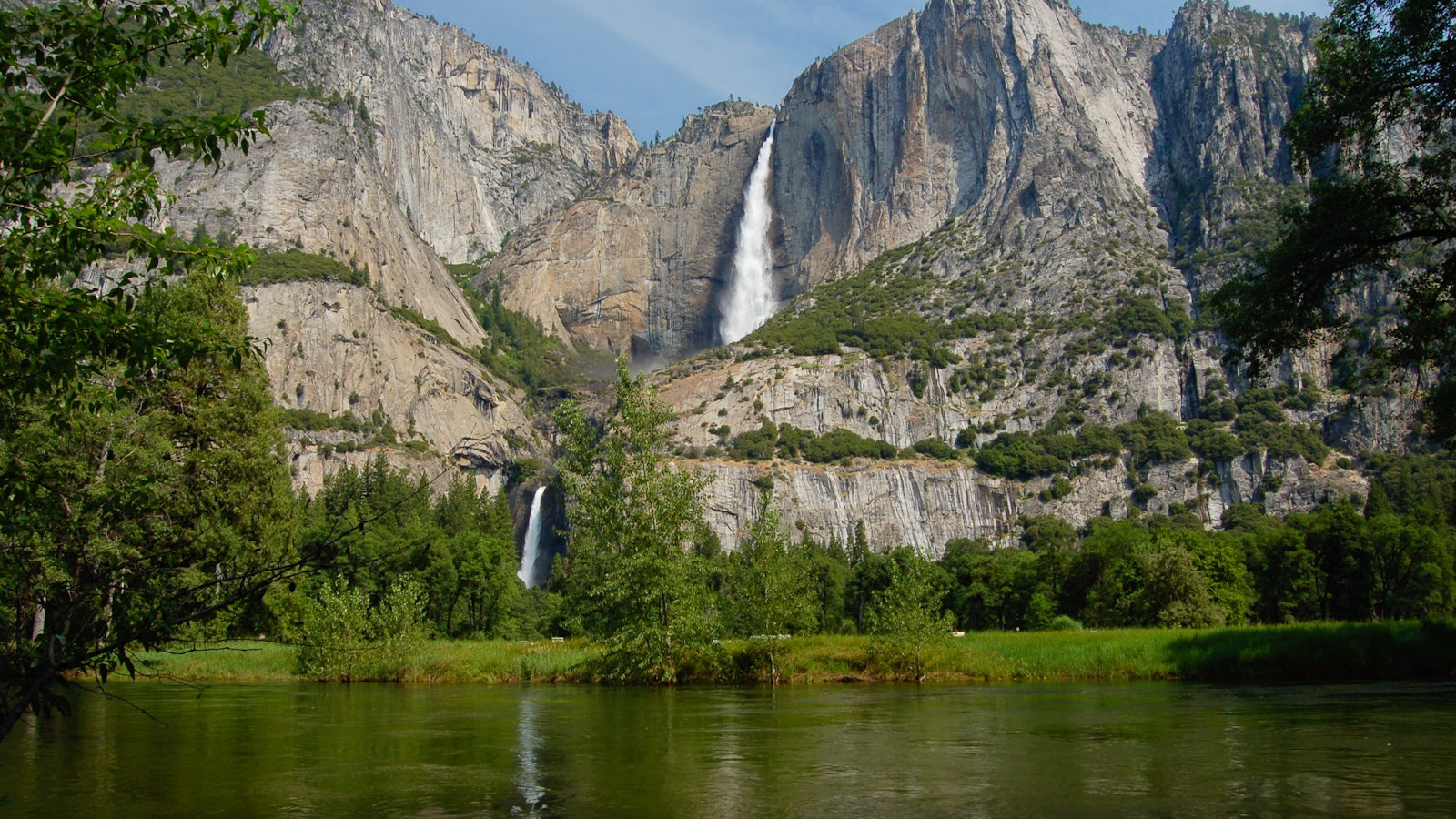 View up towards a large and smaller waterfall cascading down from a rocky mountain