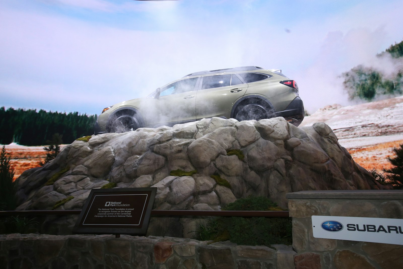 Display showcasing a new car model. A car perched atop a model of a geyser