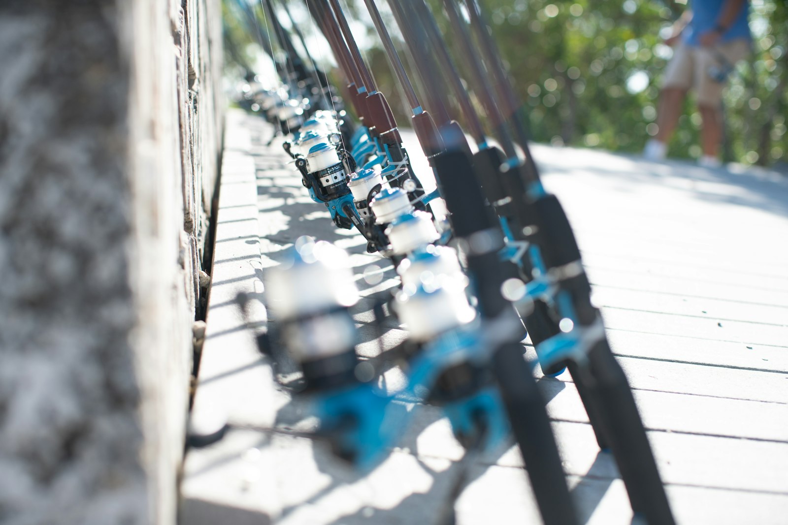 A row of fishing rods lean against the stone facade of a building
