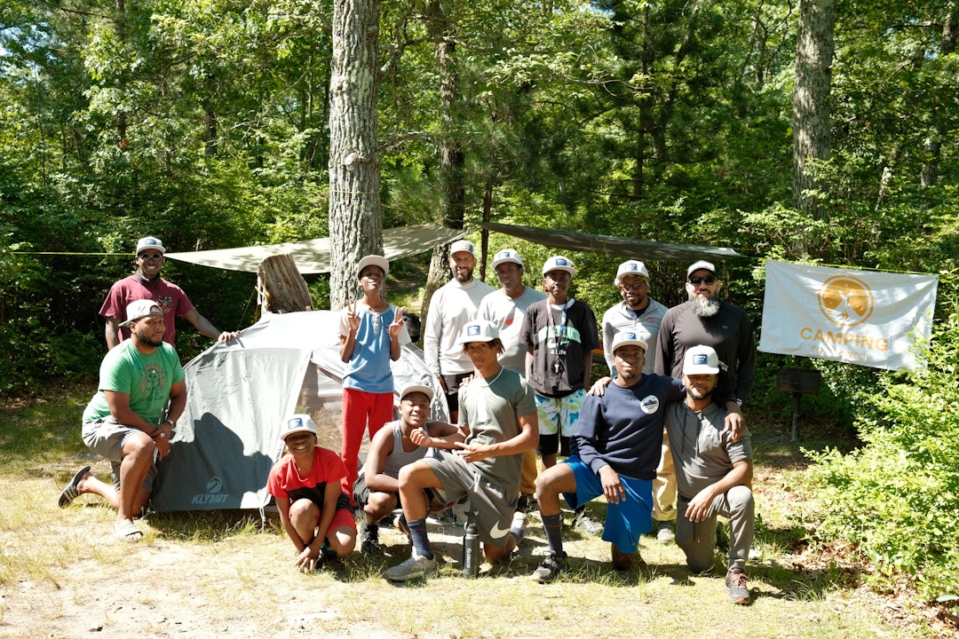 A group of young men pose for a photo in front of a campsite