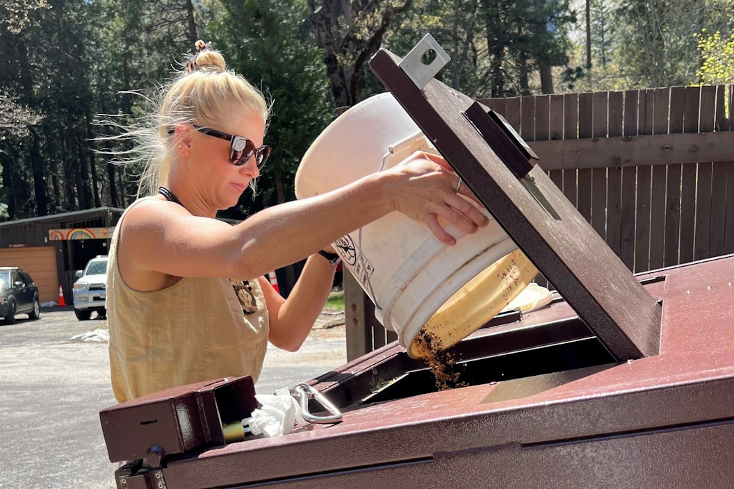 Moseley empties a compost bucket into the communal compost bin at Yosemite Village