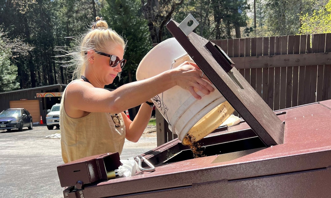 Moseley empties a compost bucket into the communal compost bin at Yosemite Village