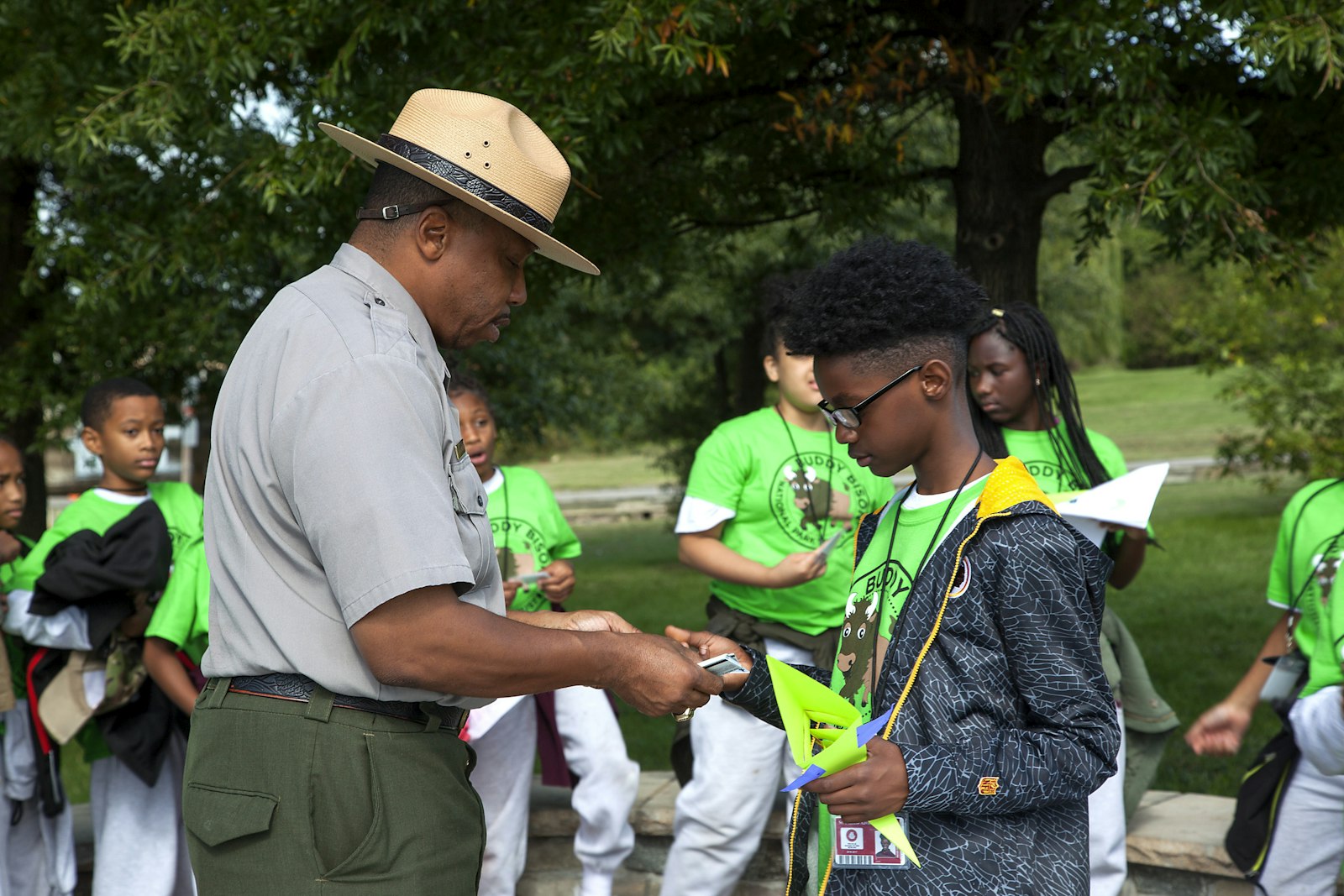 A park ranger hands a badge to a young student