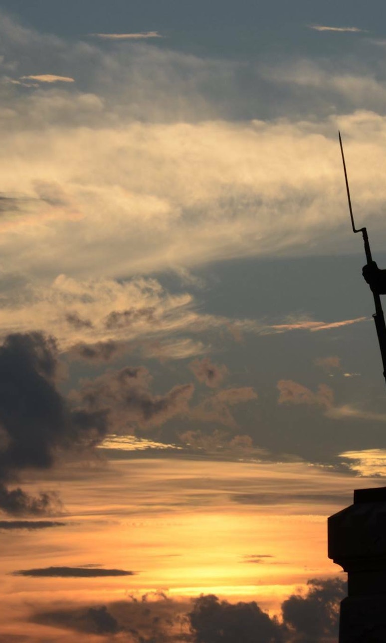 A statue at sunset depicts a soldier carrying a bayonet