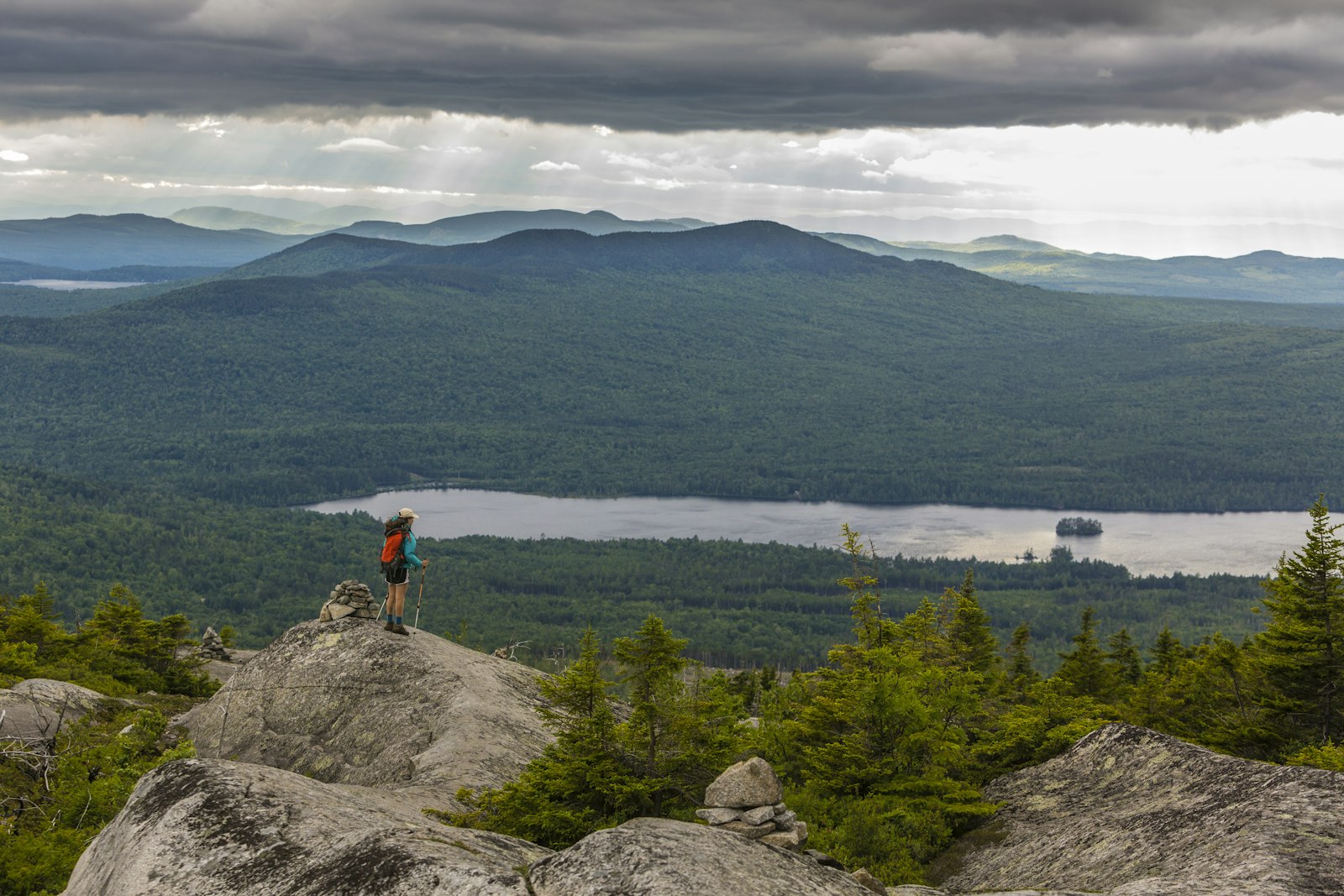 A hiker looks out from a summit