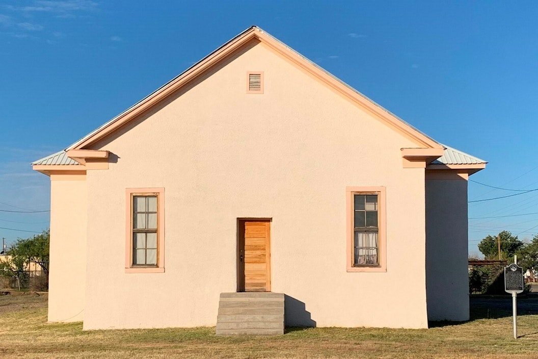 Adobe schoolhouse with two narrow windows