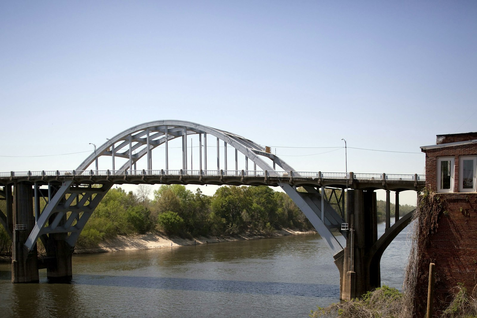 An arch winds over a steel bridge, over a river