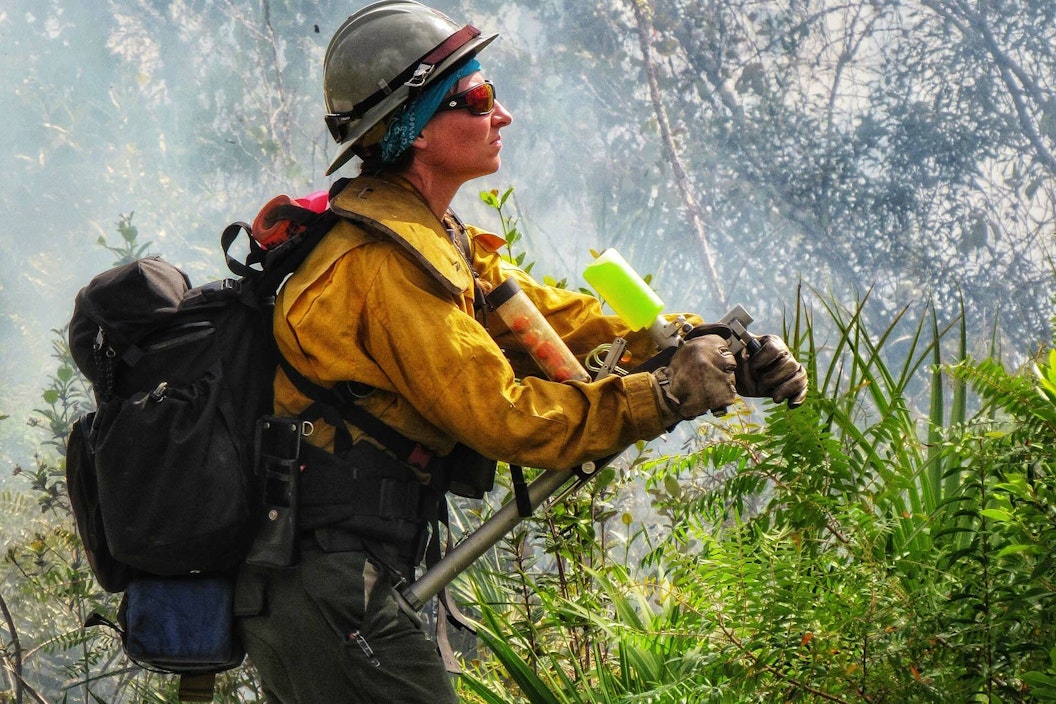 A person dressed in fire safety gear in a smoky clearing