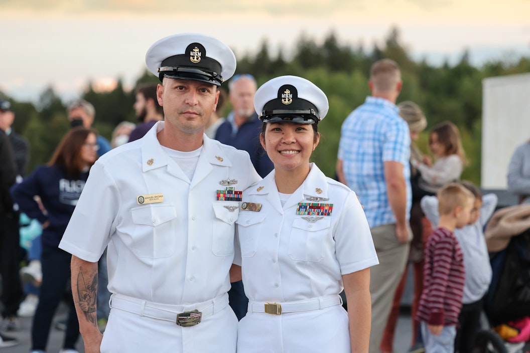 Two members of the navy, dressed in white uniforms, pose for a photograph