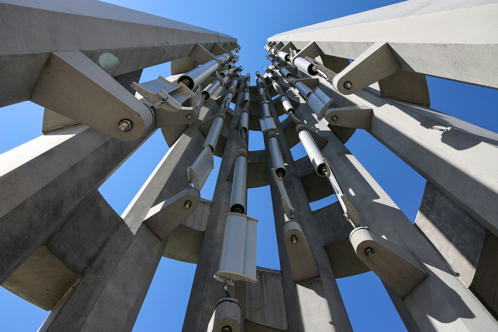 Looking upward, a structure of stone tower walls with large metal bells hung up among them