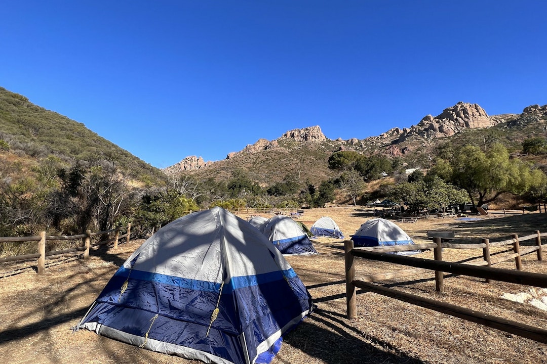 A handful of tents set up along a mountain range