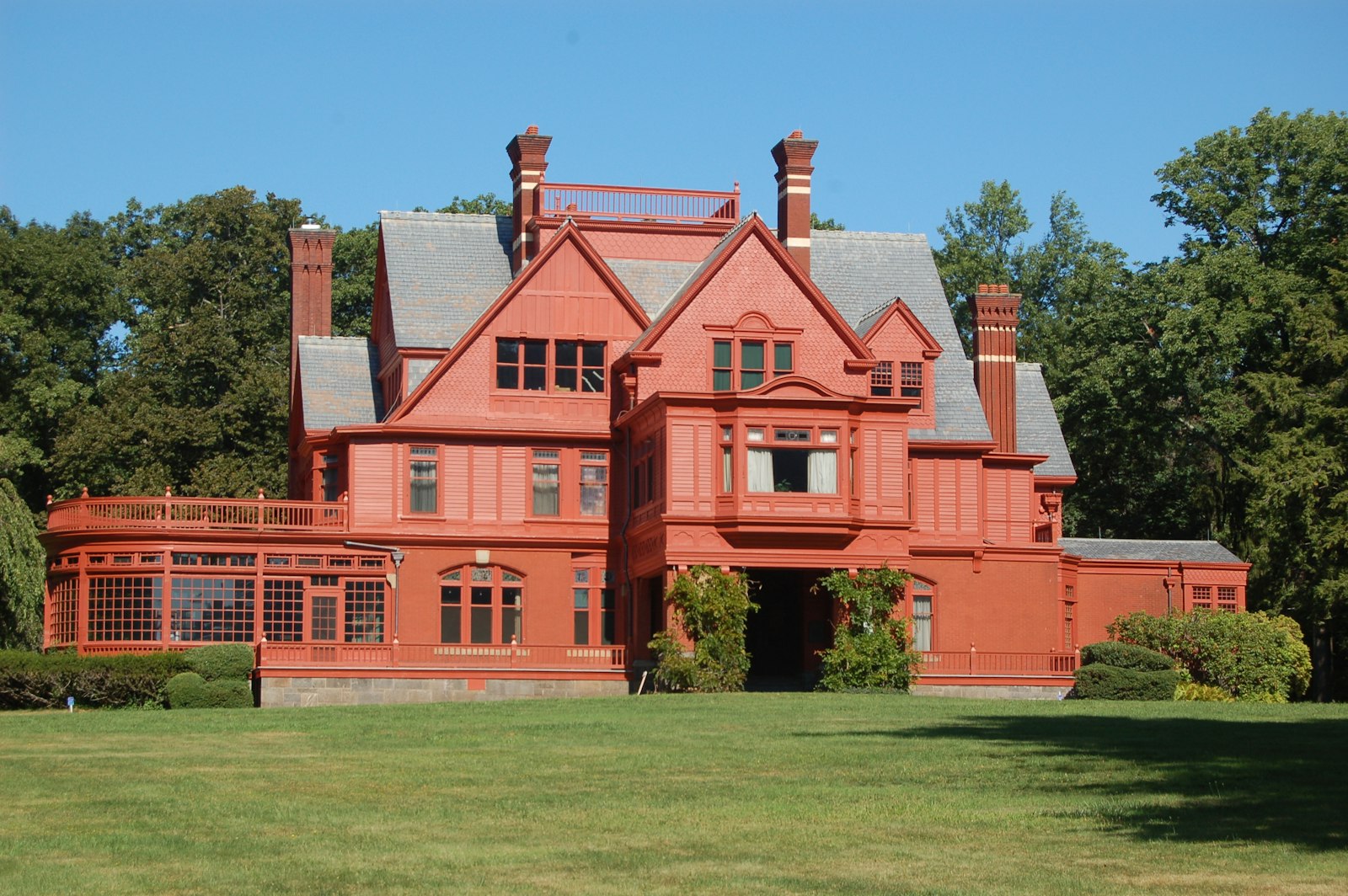 Large salmon colored mansion with several gabled roofs.