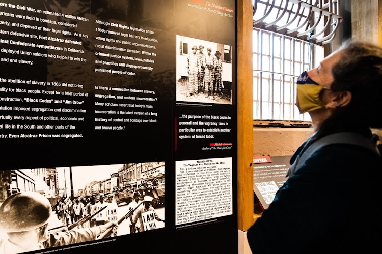 Visitor reads the Does History Matter panel with text explaining the transition from slavery, 13th amendment, and Jim Crowe. Images of the time period and quotes for subject experts included.