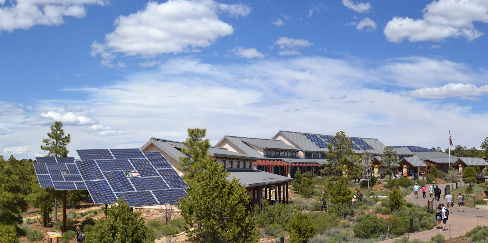 Solar panels to the left of a one-level visitor center along the edge of a canyon
