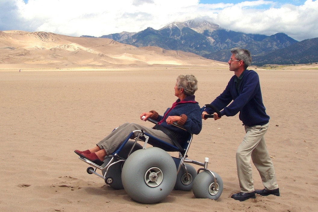 A person pushes another person using a dune wheelchair
