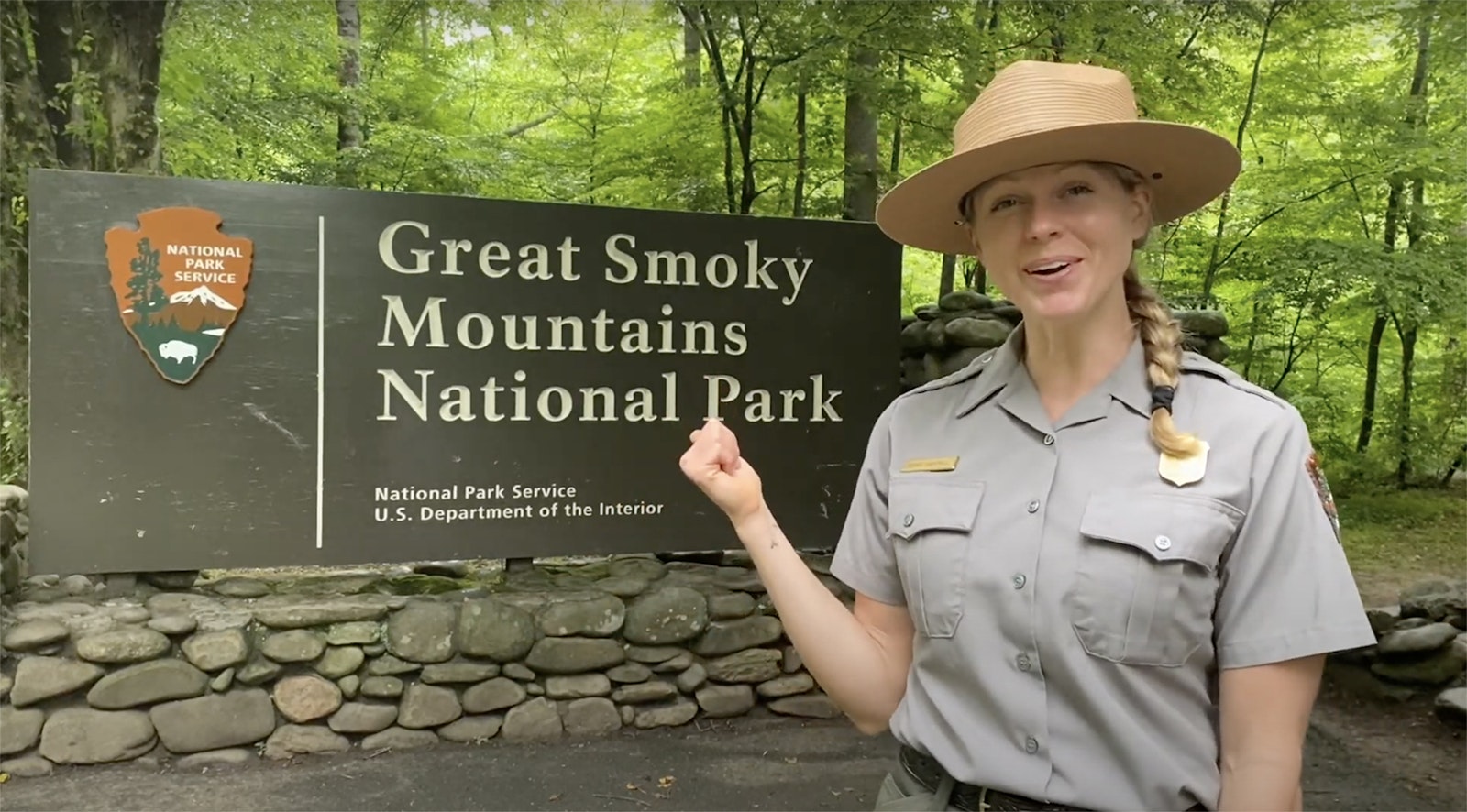 A park ranger points to a sign for Great Smoky Mountains National Park
