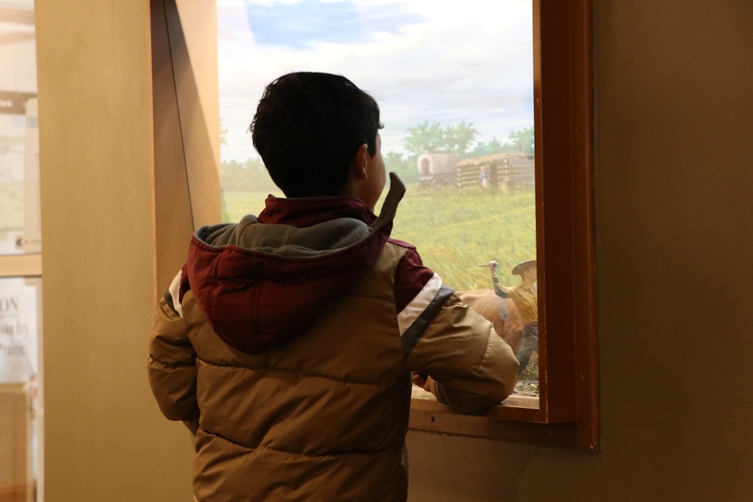 A young visitor peers through a window at an exhibit