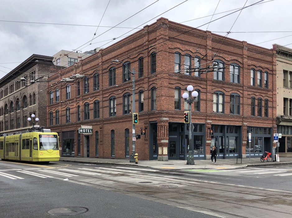 A three-story brick building with a yellow streetcar passing alongside