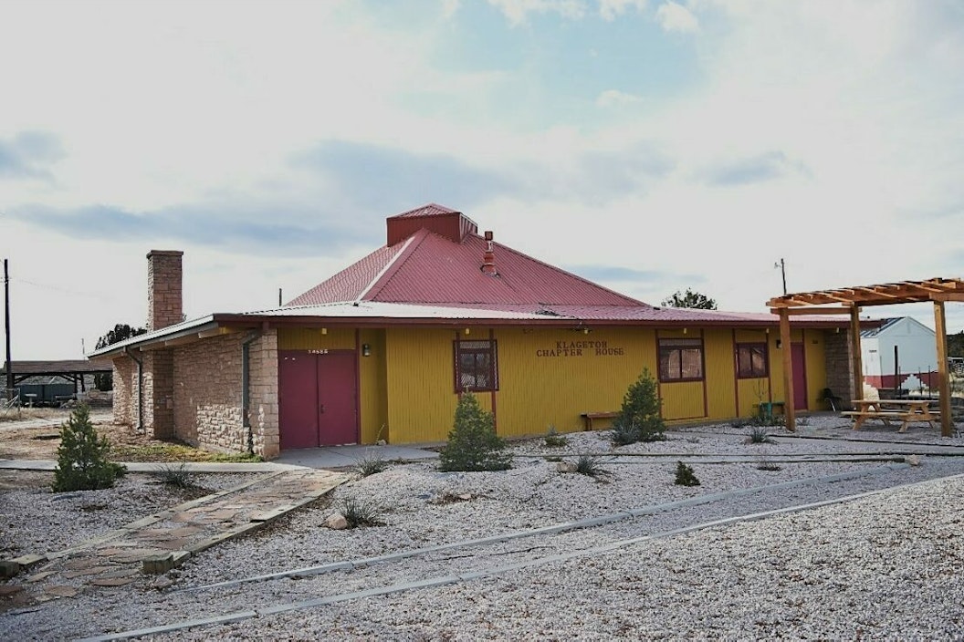 Historic photograph of a one-story building with yellow siding and a red roof