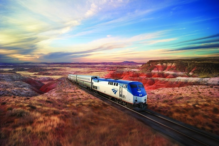 An Amtrak train runs through a desert landscape
