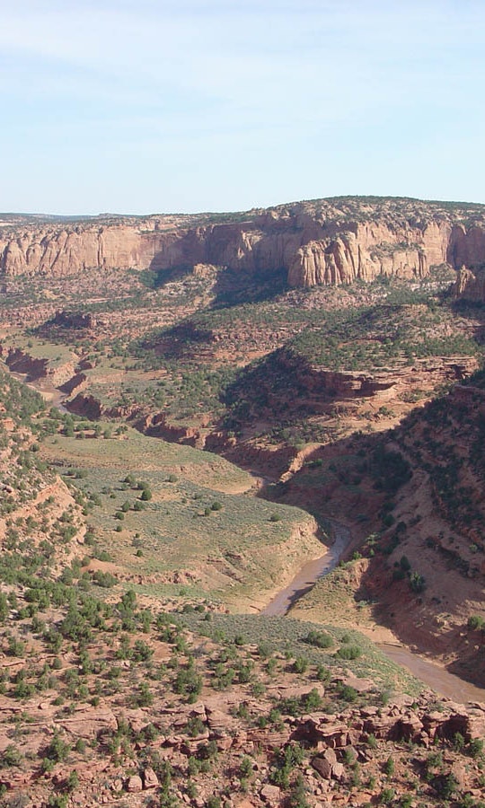 a river winds its way through a wide rocky desert canyon