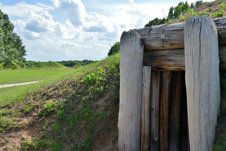 Entrance to an earthen mound, marked by large pieces of timber framing the entrance