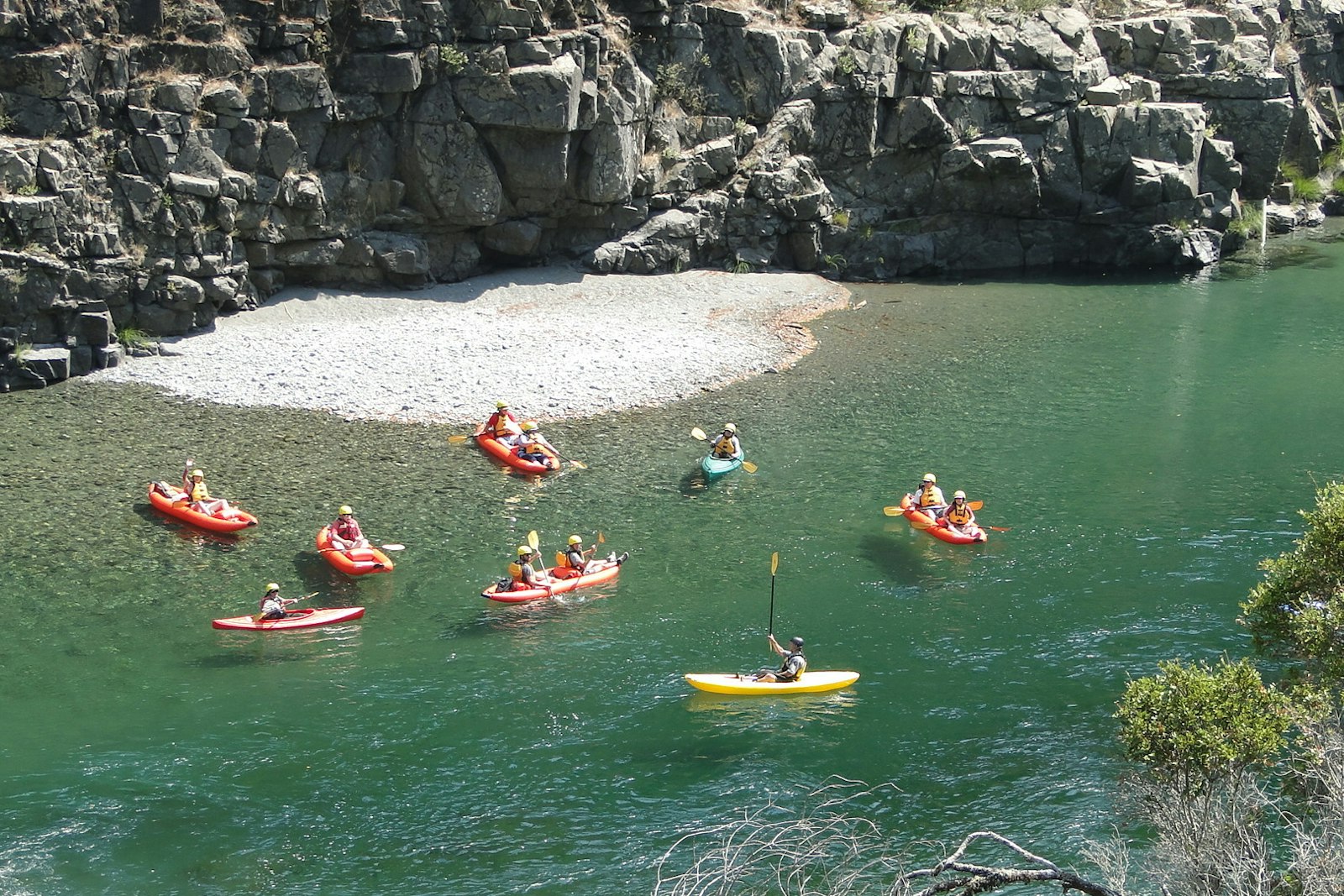 A handful of kayaks on a shallow river