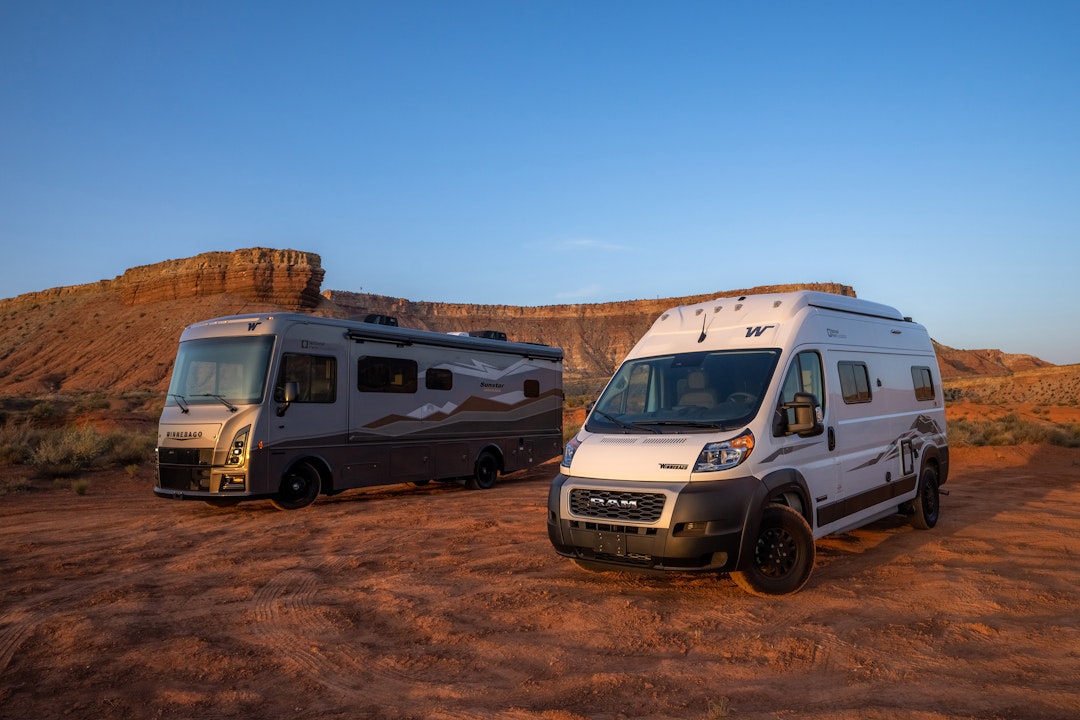 Two RVs are parked side by side amid a desert landscape