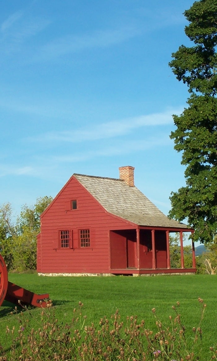 Late afternoon summer sun brings out the deep red of this one-room farmhouse
