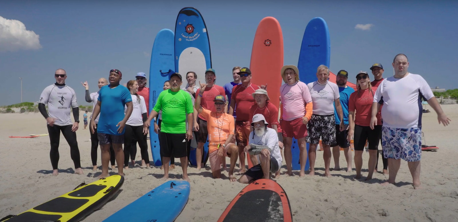 screenshot from a video depicting a group of people in surf gear posing for a photo