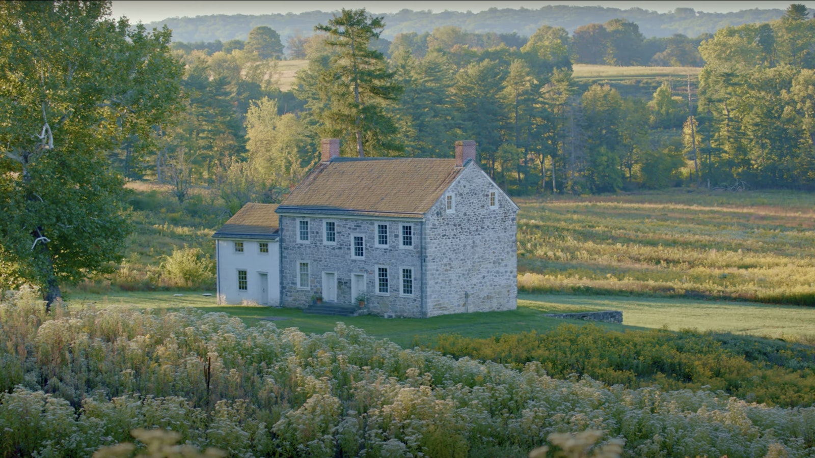 A stone farm house sits among a field