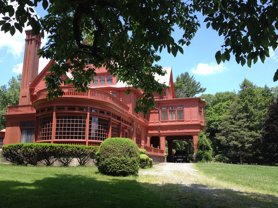 Through a canopy of trees, a three story red building