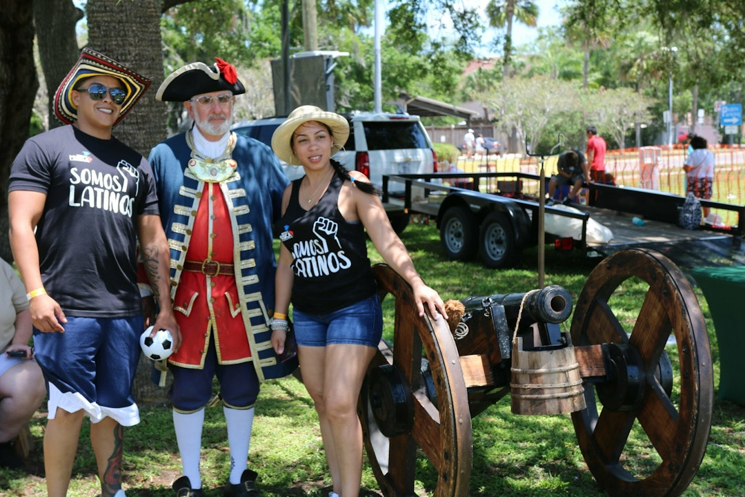 Two people pose for a photo next to a living history solider and a historic cannon